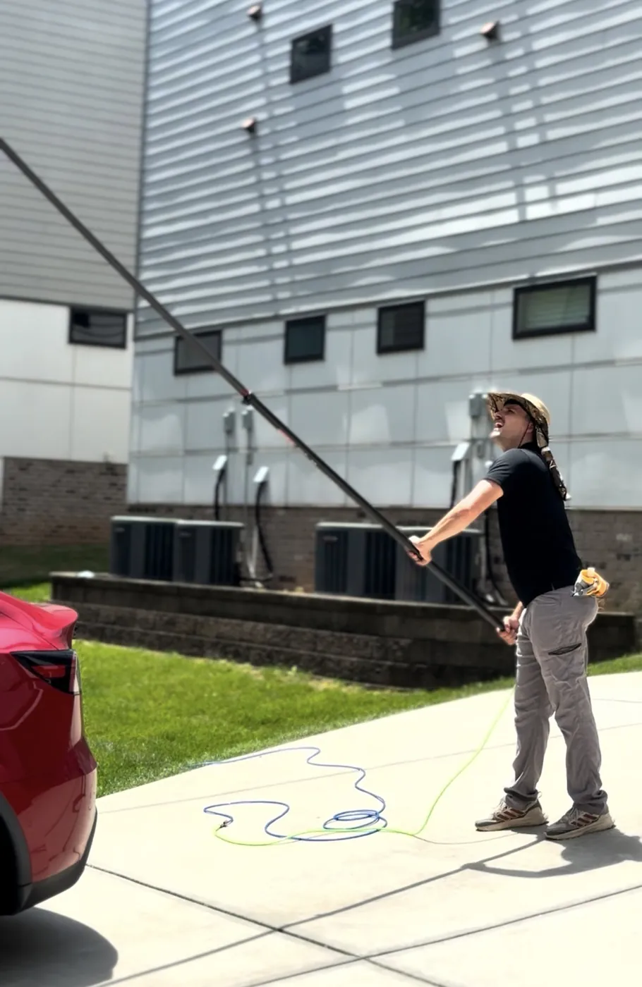Technician reaching third-storey windows with a long carbon-fibre waterfed pole from the driveway.
